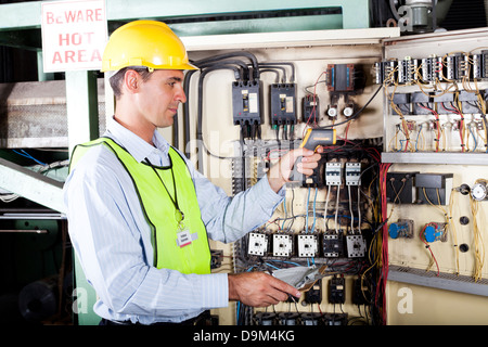 male Caucasian electrician checking industrial machine control box temperature Stock Photo