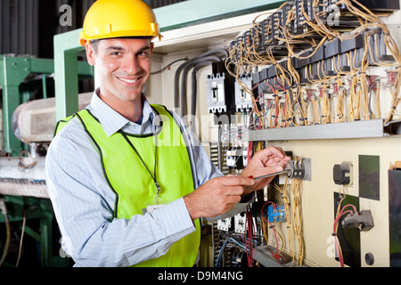 happy male Caucasian technician repairing industrial machine control box Stock Photo