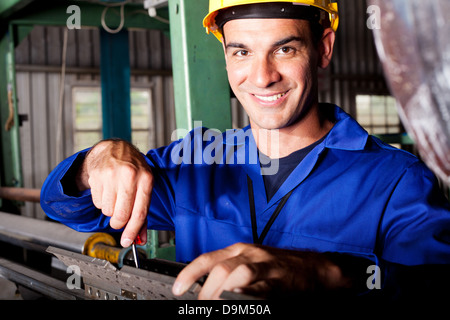 happy Caucasian mechanic repairing heavy industry machine Stock Photo