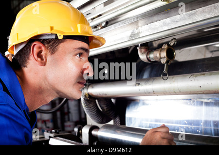 industrial machine operator checking on machine while it's running Stock Photo