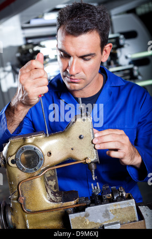 mechanic repairing industrial sewing machine in factory Stock Photo