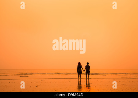 sunset silhouettes of loving couple on the beach Stock Photo