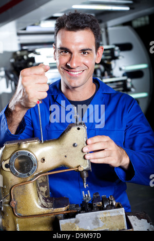 happy industrial mechanic repairing sewing machine Stock Photo