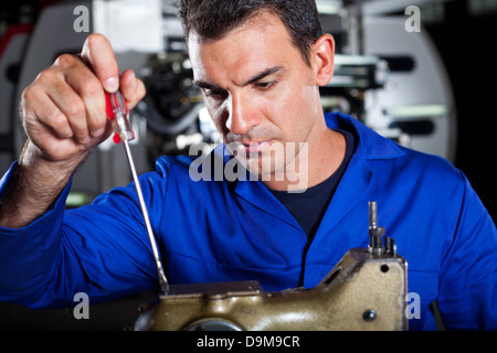 mechanic repairing industrial sewing machine Stock Photo