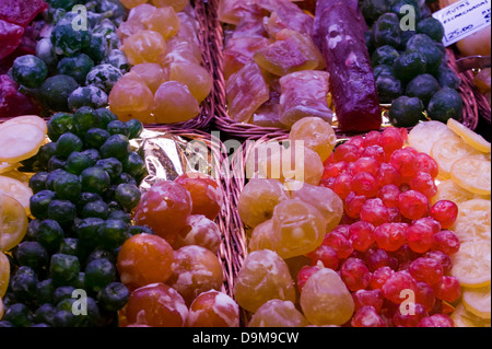 A selection of dried glace fruits displayed in baskets at a stall in La Boqueria Market in Barcelona Spain Stock Photo