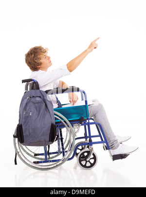 disabled teen boy sitting on wheelchair and pointing on white background Stock Photo