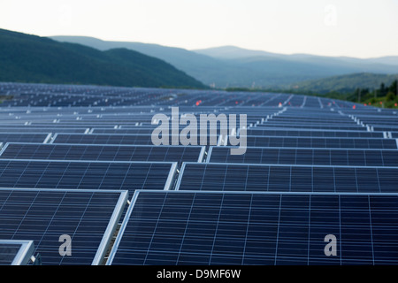 The sun sets on a field of solar panes near the completion of installation in Adams, Massachusetts. Stock Photo