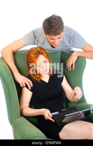 a pretty woman is helping a man with the use of the computer Stock Photo