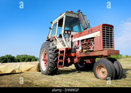 An old tractor in a freshly mowed field. Stock Photo