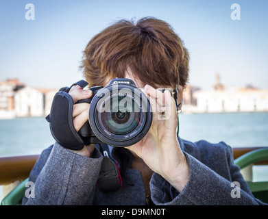 Face on image of female photographer focuses camera Stock Photo