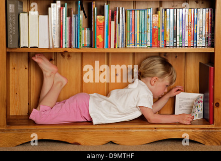 girl reading in a bookcase. Stock Photo