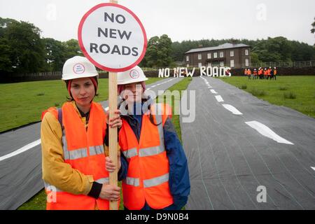 Cheshire, UK. 23 June 2013. Natalie Hynde Daughter of Chrissie Hynde and Ray Davies and Gabriele join 20 activists dressed in roadbuilders' high viz clothing rolling out a fake road in the field immediately below Crag Hall, Cheshire in whose grounds the Chancellor of the exchequer George Osborne has a residence. The protest was made to highlight the expected release of money for roadbuilding schemes throughout  the UK in the imminent spending reivew on Wednesday 26th June Credit:  adrian arbib/Alamy Live News Stock Photo