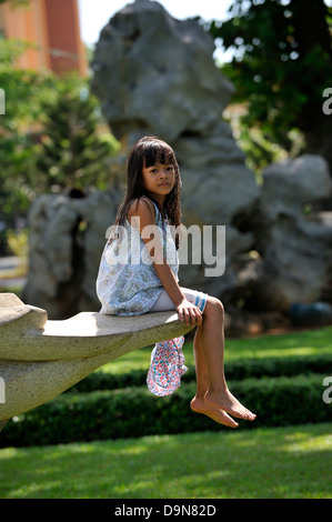 Vietnamese child sitting on sculpture in park. Vung Tau, Vietnam Stock Photo