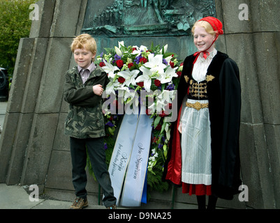 In Reykjavik, on Iceland's independence anniversary, two youngsters pose at a memorial--the girl in national dress and red cap Stock Photo