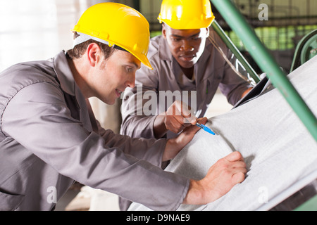 two textile workers checking fabrics quality on QC table Stock Photo