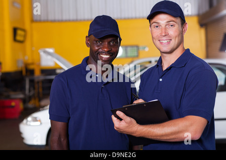 happy vehicle service center manager and worker inside workshop Stock Photo