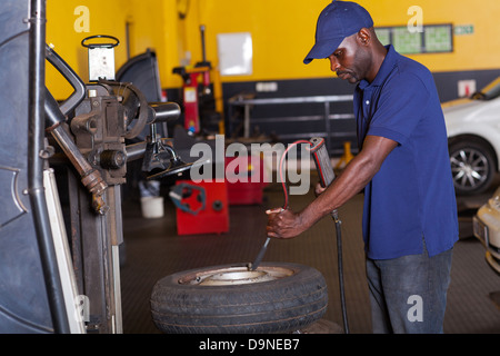 African auto mechanic pumping car tyre Stock Photo