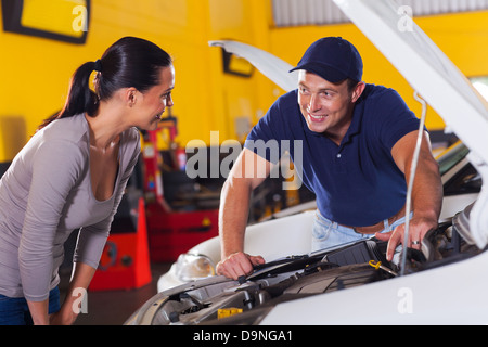 trustworthy auto technician talking to female customer in garage Stock Photo