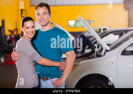 happy couple taking their car for service and waiting inside garage Stock Photo