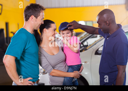 friendly African American auto mechanic playing with customer's little girl Stock Photo