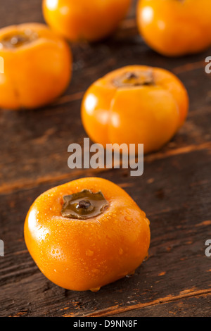 Organic Orange Persimmon Fruit against a background Stock Photo