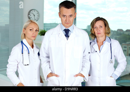 Three clinicians in white coats tired after working week Stock Photo