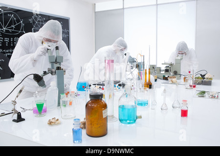 general-view of three people observing and analysig chemical reactions in a lab using colorful substances and lab tools on a lab Stock Photo