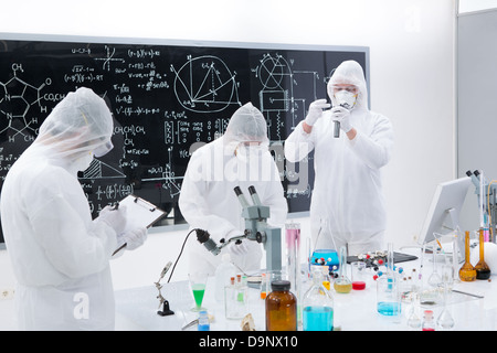 general-view of three scientists in a chemistry lab manipulating lab tools, testing and using chemical techniques around a lab t Stock Photo