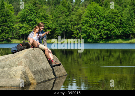 Young hikers couple sitting on rock by the lake Stock Photo