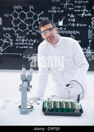 close-up of a scientist in a chemistry lab conducting a seedlings experiment on a lab table with lab tools and a blackboard on t Stock Photo