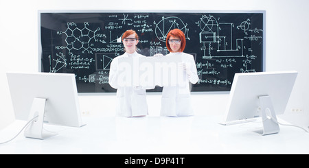 general-view of two students in a chemistry lab around a lab table with two pc monitors on it holding in hands an empty banner a Stock Photo