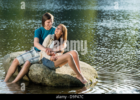 Couple in love sitting on a rock by the lake Stock Photo