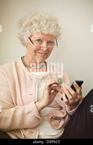 Old lady texting someone using her cell phone Stock Photo