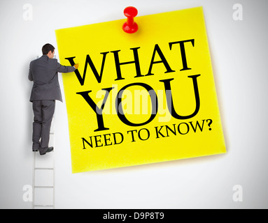 Businessman standing on ladder writing what you need to know Stock Photo