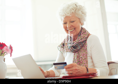 Old woman happy doing her shopping online using a credit card Stock Photo