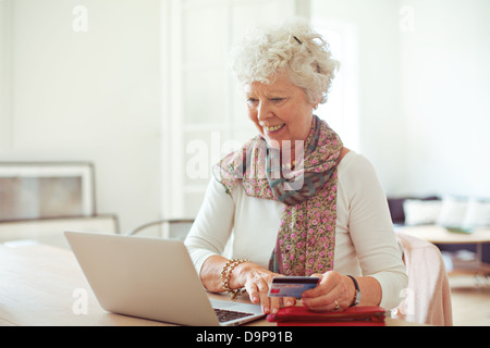 Happy old lady doing some shopping online using her laptop Stock Photo