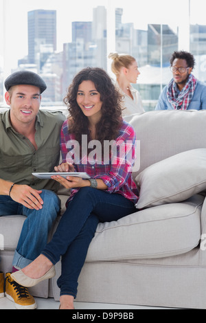 Smiling workers working on a tablet computer on a couch Stock Photo