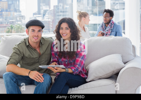 Employees working on a tablet computer on a couch Stock Photo