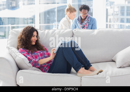 Beautiful worker using tablet pc while laying on a couch Stock Photo