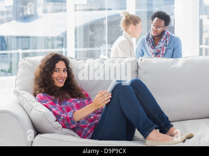 Smiling worker using tablet pc while laying on a couch Stock Photo