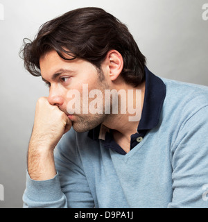 A brunette man with longer hair in blue pullover being depressed Stock Photo