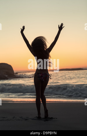 Woman raising arms on the beach Stock Photo