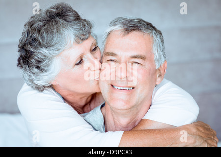 Woman kissing the cheek of her husband in the bed Stock Photo