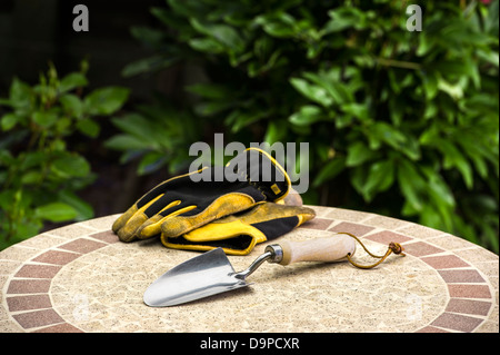 Hand trowel with gloves on a garden table. Stock Photo