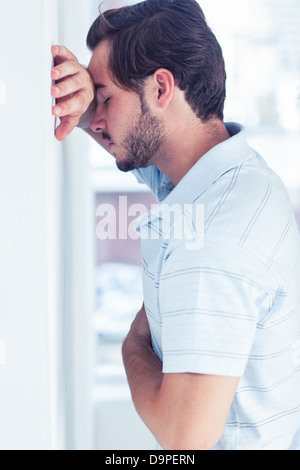 Stressed man leaning against a wall Stock Photo