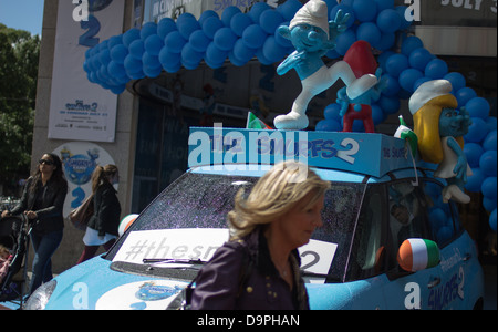 Three figurines of smurfs on top of a promotional car. Stock Photo