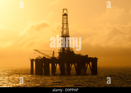 Silhouette of an offshore floating oil drilling rig. Deep sea at sunset/sunrise time. Stock Photo