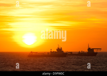 silhouette of offshore supply vessels floating at Campos basin, Rio de Janeiro, sunset time. Stock Photo