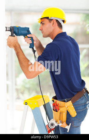 cctv camera installer drilling on the wall Stock Photo