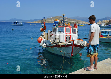 Young man fishing on waterfront, Port of Emporio, Halki (Chalki), Rhodes (Rodos) Region, The Dodecanese, South Aegean, Greece Stock Photo